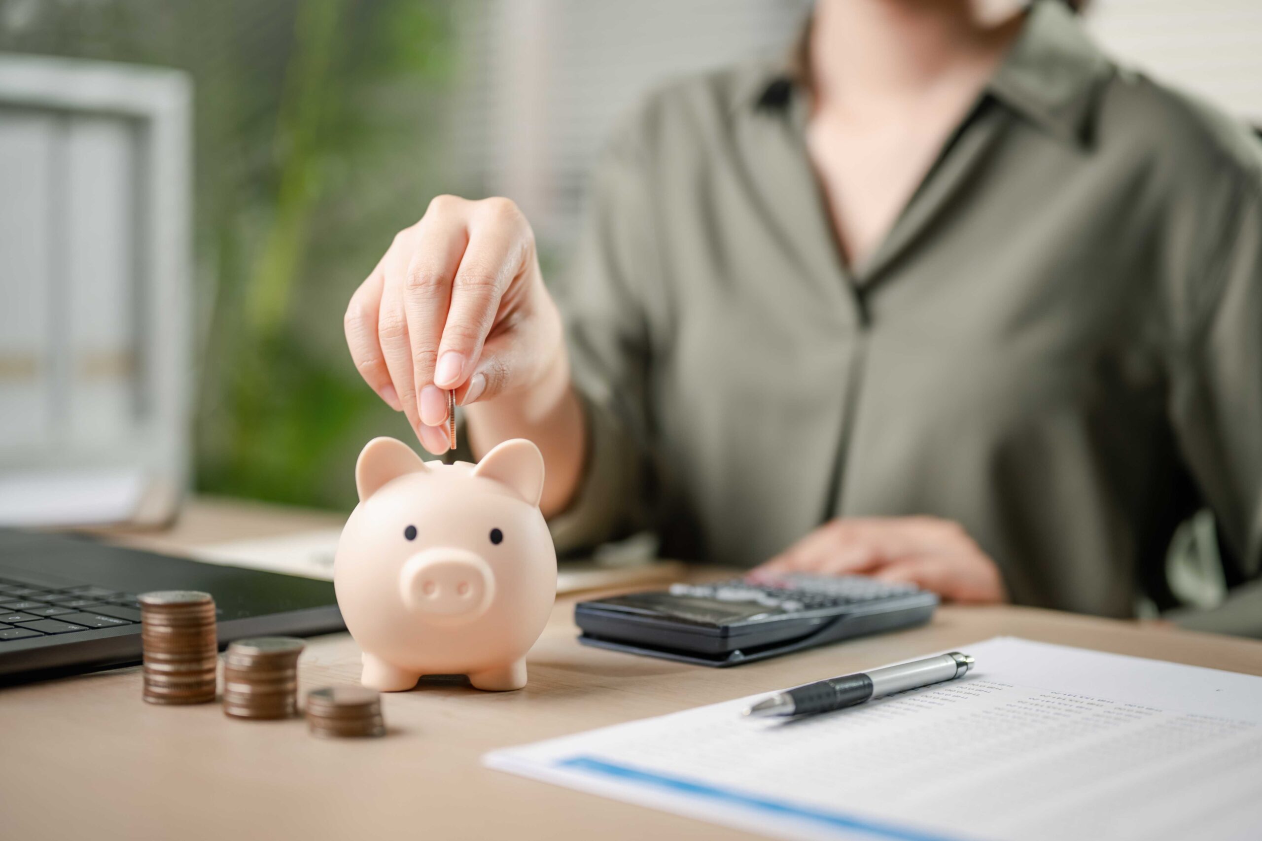 Person saving money into a pink piggybank.